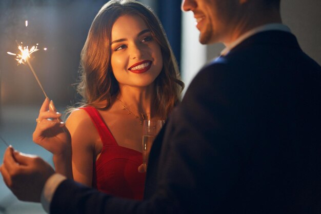 Un couple souriant fête les fêtes avec des étincelles