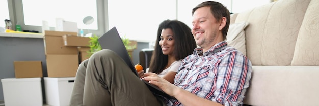 Un couple souriant et joyeux regarde une émission en ligne sur un ordinateur portable à la maison