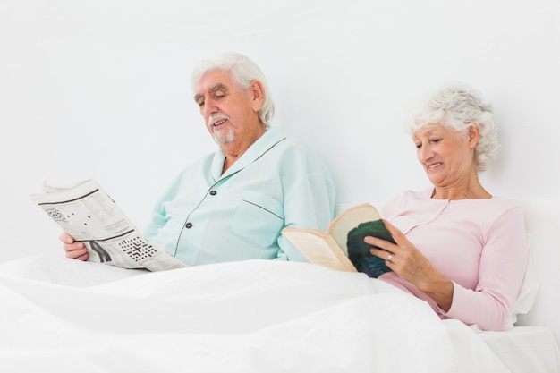 Couple souriant, lecture au lit