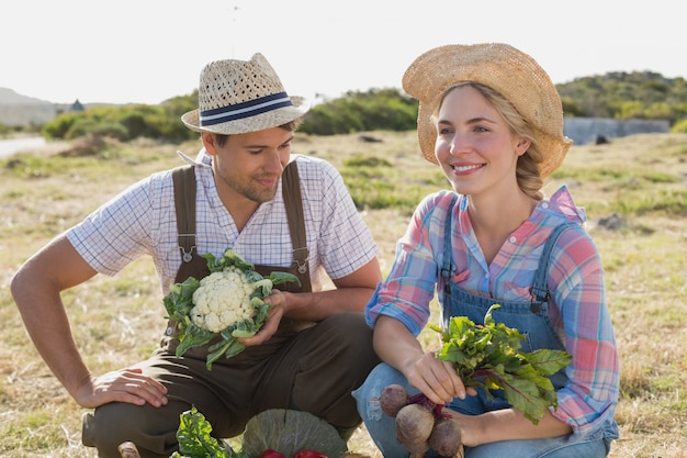 Couple souriant avec des légumes frais dans le champ