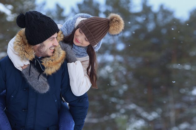 Couple souriant ludique marchant dans l'espace de copie de la forêt d'hiver