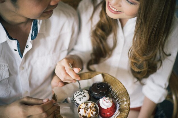 Photo couple souriant mangeant un dessert dans un café.