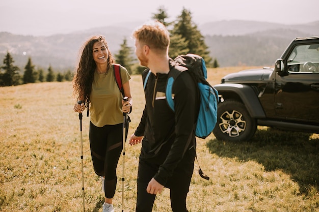 Couple souriant marchant avec des sacs à dos sur les collines vertes