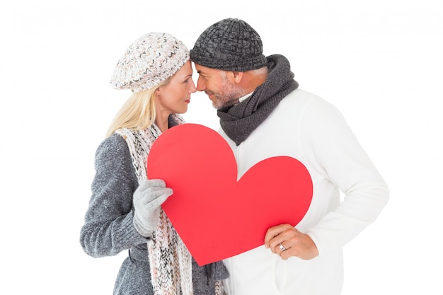 Couple souriant en mode hiver posant avec forme de coeur