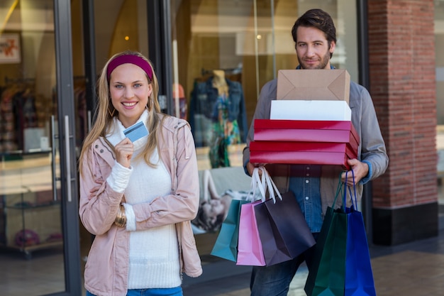 Couple souriant, montrant la carte de crédit et des boîtes de transport