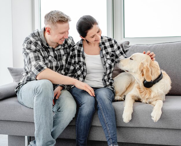 Couple souriant palming golden retriever