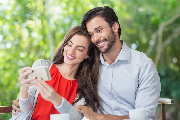 Couple souriant prenant un selfie en position assise