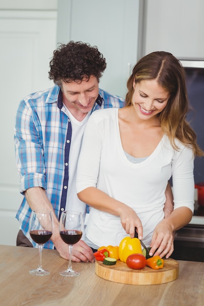 Couple souriant prépare une salade de légumes