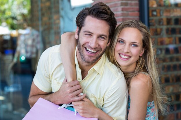 Couple souriant avec des sacs à provisions embrassant