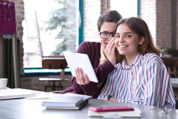 Couple souriant à table avec tablette