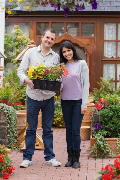 Couple souriant tenant un plateau de plantes