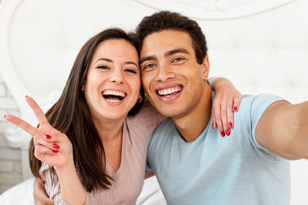 Photo couple souriant tir moyen prenant un selfie