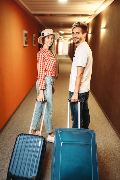 Couple souriant avec valise dans le couloir de l'hôtel