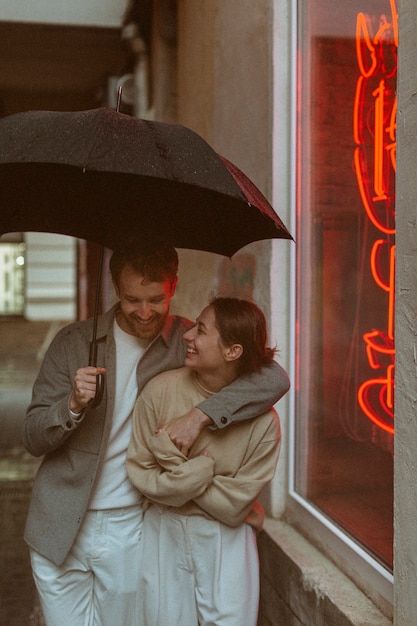 Photo couple souriant vue de face avec parapluie