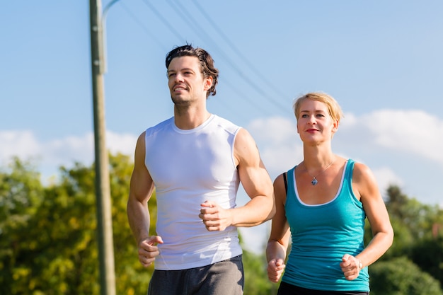 Couple de sport courir et faire du jogging dans une rue rurale