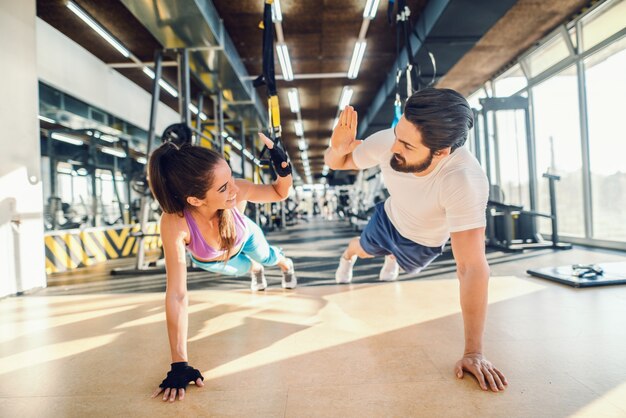 Couple sportif faisant des pompes et donnant cinq hauts. Intérieur du gymnase.