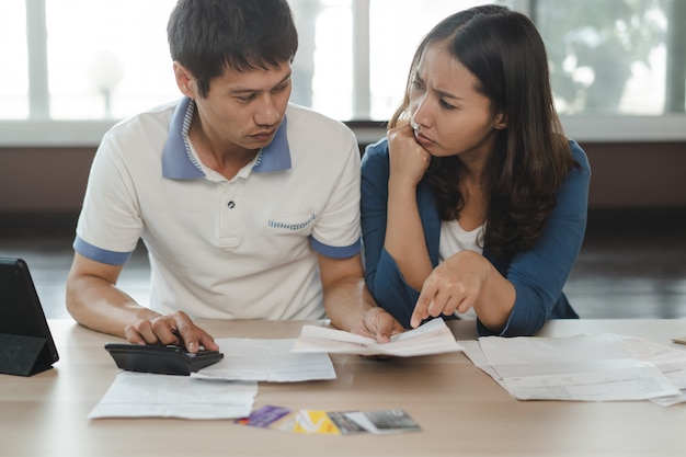 Couple stressé calculant la dette de carte de crédit.