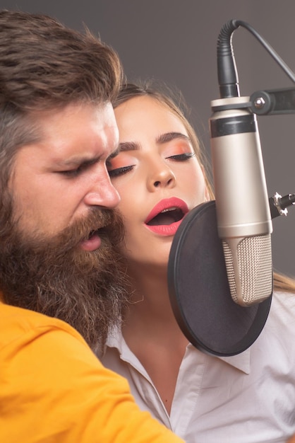 Couple en studio d'enregistrement performance musicale chanteuse vocale chantant une chanson avec un microphone