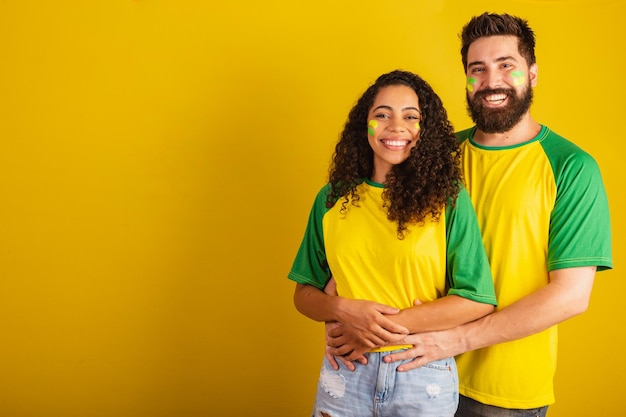 Couple de supporters de football brésiliens vêtus aux couleurs de la nation femme noire homme caucasien ensemble romantique