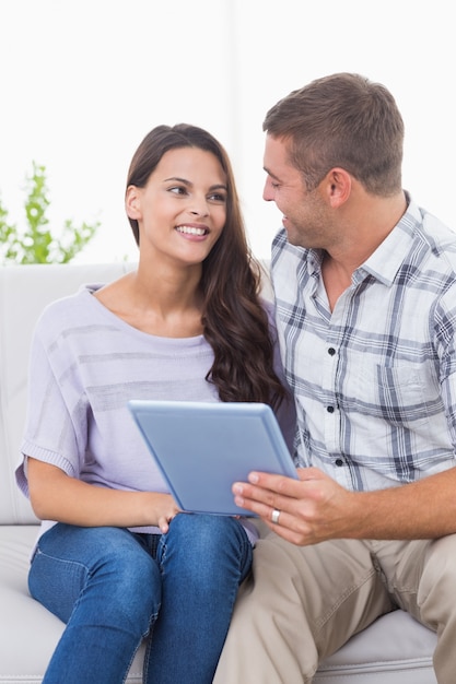 Couple avec tablette PC assis sur le canapé