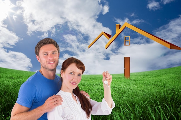 Couple tenant les clés de la maison contre un champ vert sous un ciel bleu