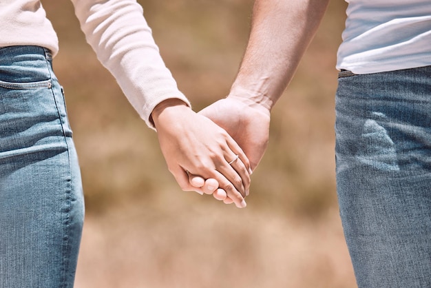 Couple tenant par la main l'amour et les soins montrant l'affection, l'amitié et la romance lors d'une promenade ensemble dans la nature