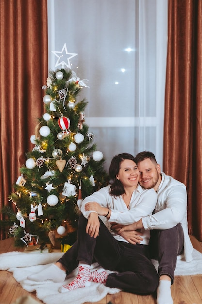 Couple tirant devant un sapin de noël décoré