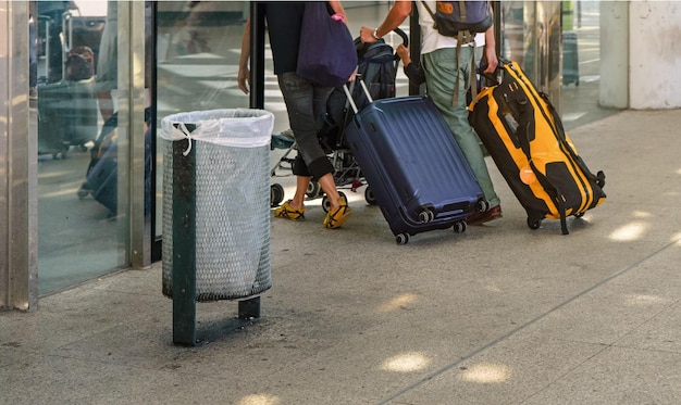 Couple tirant leurs bagages de chariot derrière eux à l'aéroport, vue de dos, seuls les jambes et les bagages au sol sont visibles