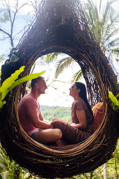 Un couple de touristes assis sur un grand nid d'oiseau sur un arbre sur l'île de Bali
