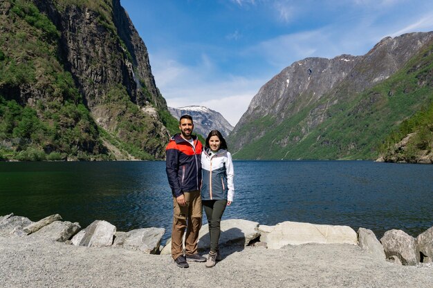 Couple de touristes au pied du fjord et entouré de hautes montagnes à Gudvangen Norvège