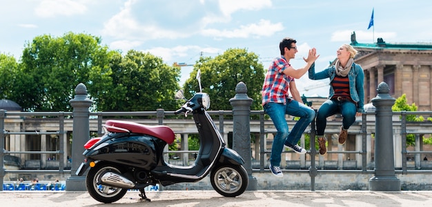 Couple de touristes faisant un arrêt pendant l'excursion Vespa près de l'ancienne galerie nationale de Berlin