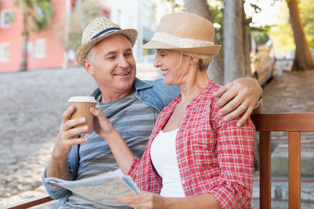 Couple de touristes heureux boire du café sur un banc dans la ville