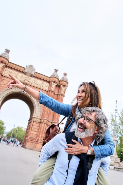 Un couple de touristes matures et attrayants montrant du doigt quelque chose dans la rue de la ville.