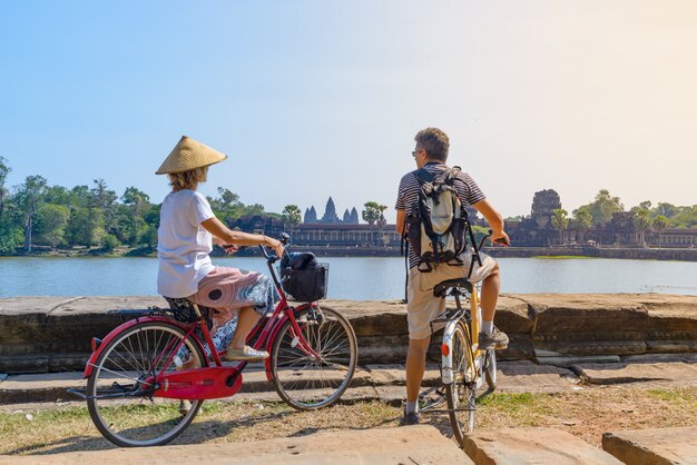 Couple de touristes à vélo dans le temple d&#39;Angkor, Cambodge. Façade principale d&#39;Angkor Wat