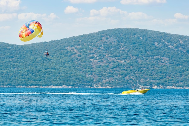 Couple de touristes volant sur un parachute coloré. Émotions humaines positives. Loisirs d'été en mer - Bodrum, Turquie.