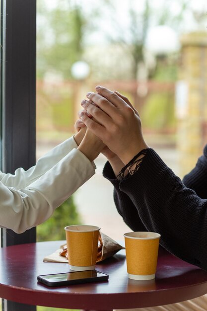 Un couple en train de boire un café en se tenant par la main