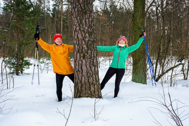 Couple en train de marcher avec les bras tendus dans la forêt d'hiver enneigée