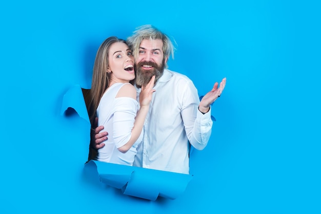 Couple à travers le trou dans l'espace de copie de papier bleu pour le texte ou le slogan