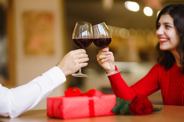 Couple trinquant avec du vin rouge Les amoureux s'offrent des cadeaux Beau dîner romantique