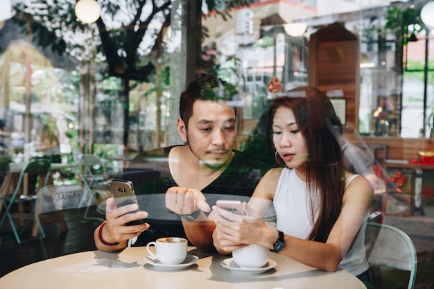 Couple en utilisant un téléphone dans un café