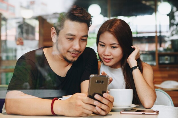 Couple en utilisant un téléphone dans un café