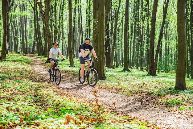 Couple à vélo dans la forêt par temps chaud