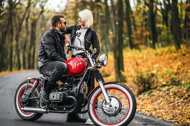 Couple de vélo élégant avec une moto rouge