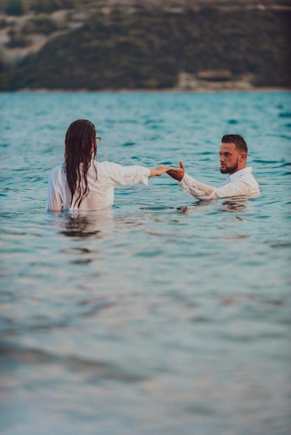 Un couple en vêtements se tenant la main dans la mer Photo de haute qualité