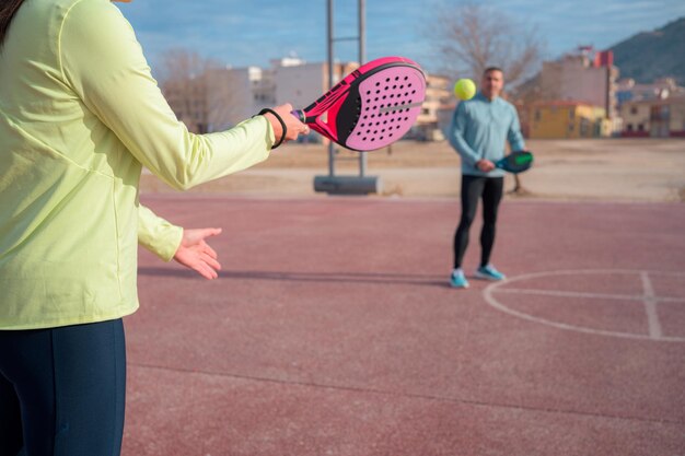 Un couple en vêtements de sport joue au paddle tennis avec des raquettes