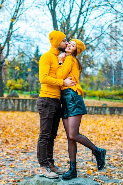 Couple vêtu de cols roulés jaunes et de chapeaux jaunes dans le parc à l'automne