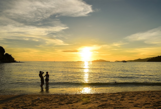 Couple voir le coucher de soleil romantique au bord de la mer