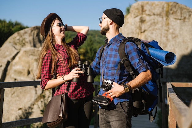 Un couple voyageant par les montagnes portant des vêtements hipster avec sac à dos, appareil photo vintage et jumelles