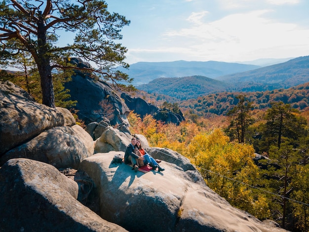 Couple voyageur assis au sommet du rocher avec un beau paysage de forêt d'automne