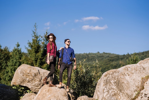 Un couple de voyageurs debout ensemble sur les rochers à la montagne sur le fond de ciel bleu
